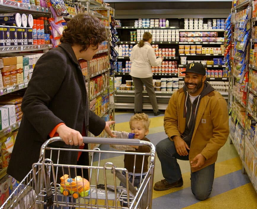 Parents grocery shopping with baby.