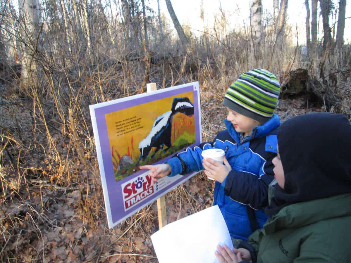 Children reading a StoryTRACKS sign.